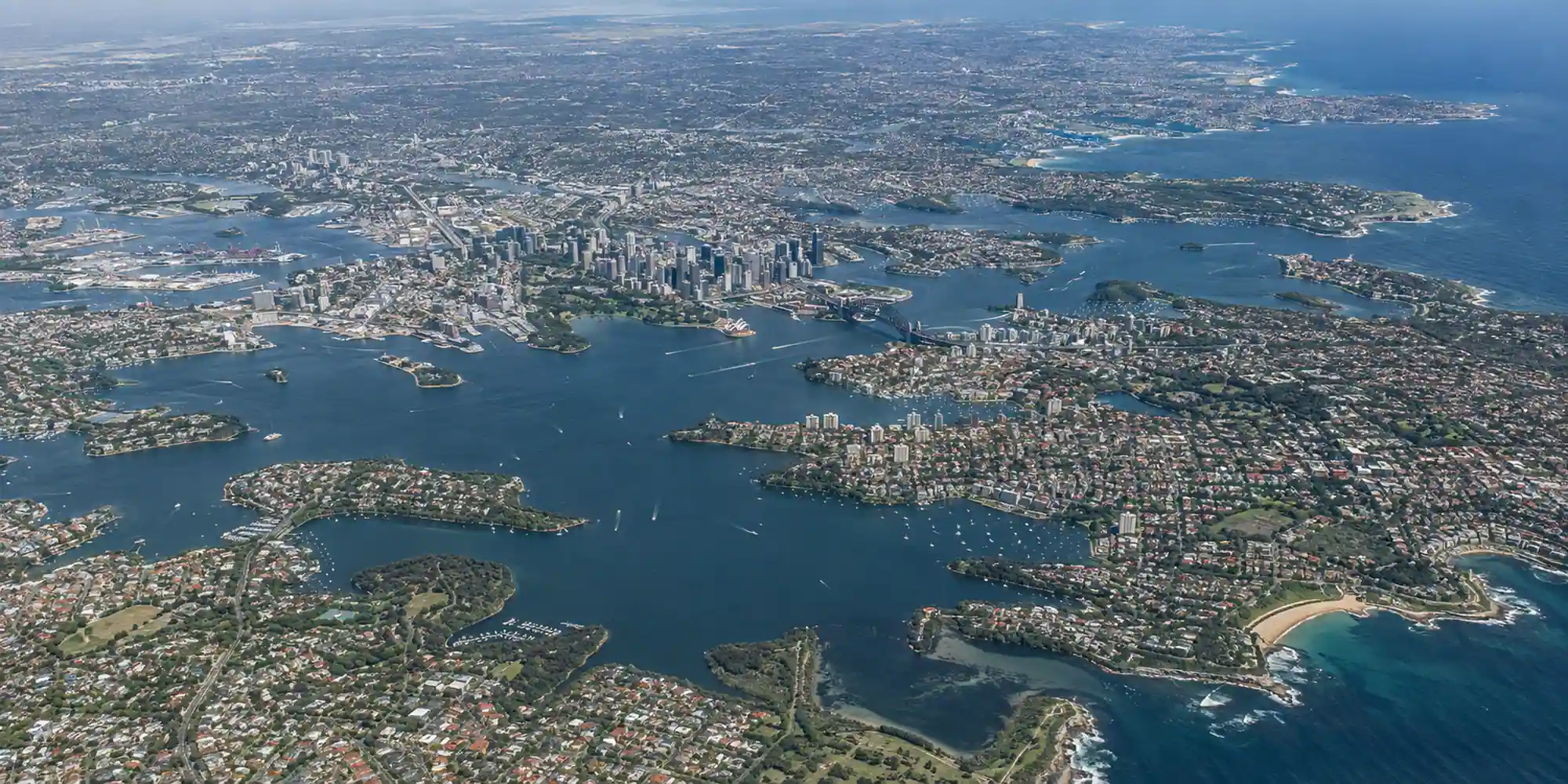 High aerial view of the Sydney metropolitan area showing the coastline and road network
