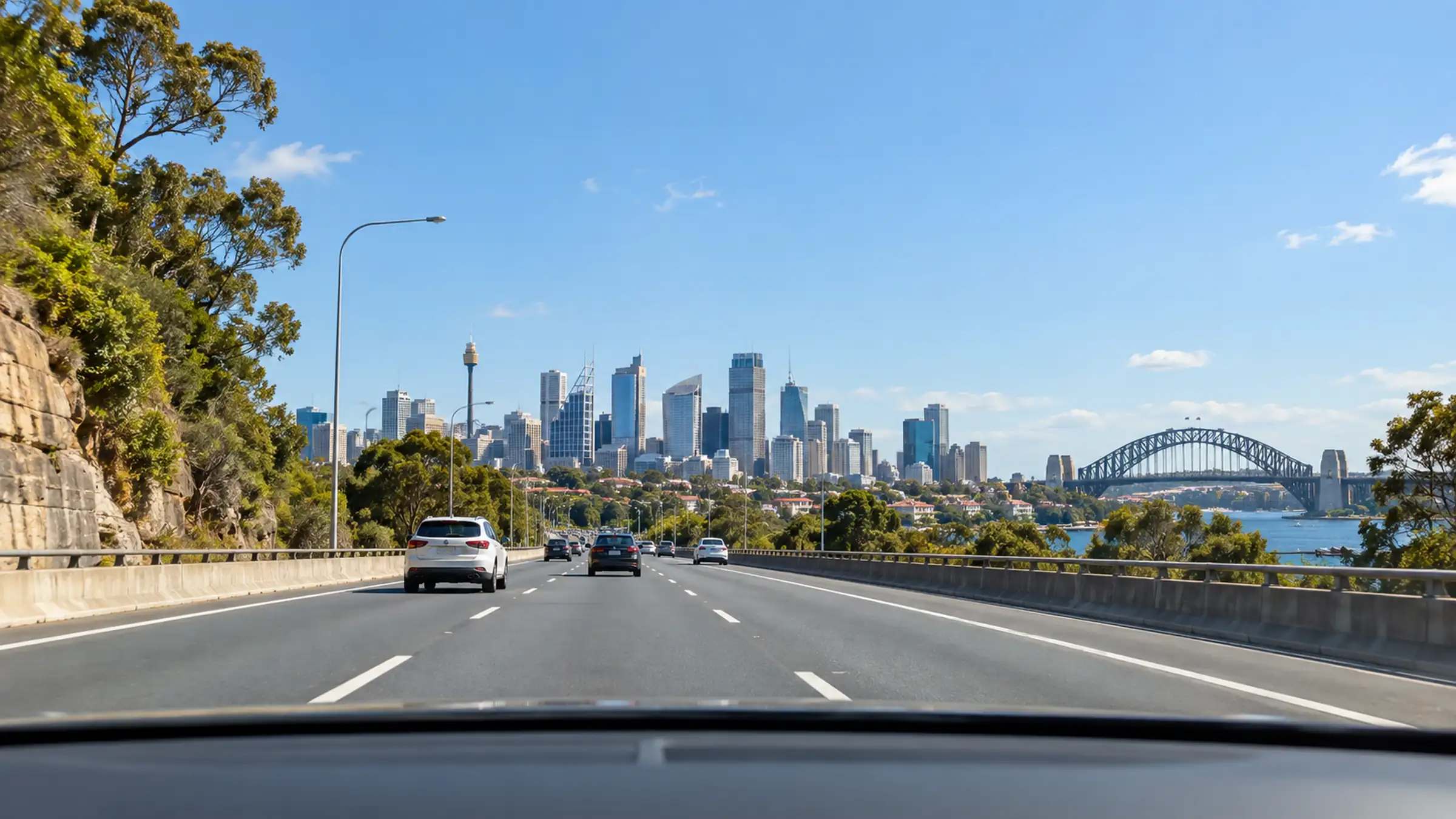 View through a windscreen along a Sydney arterial road toward the city skyline