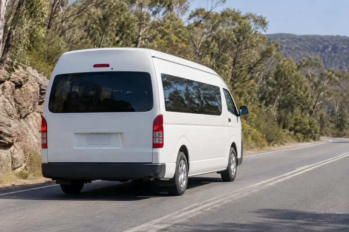 Rear view of an extended eleven seat van on an open road