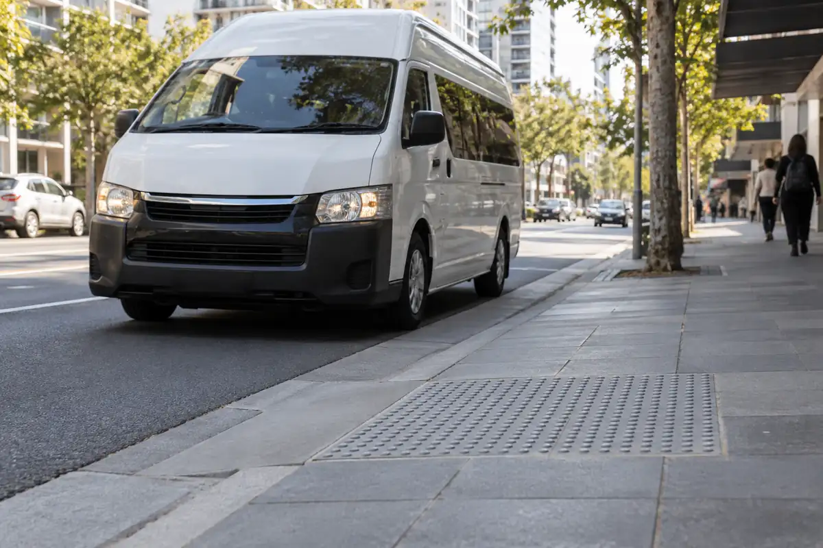 Accessible van pulling in beside a kerb ramp and tactile paving
